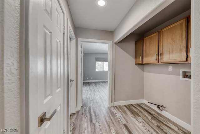 laundry room featuring cabinet space, light wood-style flooring, baseboards, and washer hookup