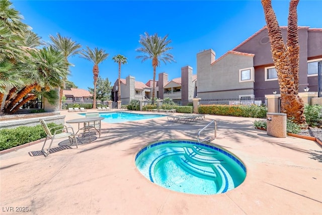 community pool featuring a community hot tub, fence, a patio, and a residential view