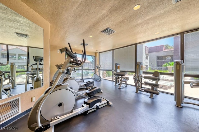 gym with a textured ceiling, a wall of windows, and recessed lighting