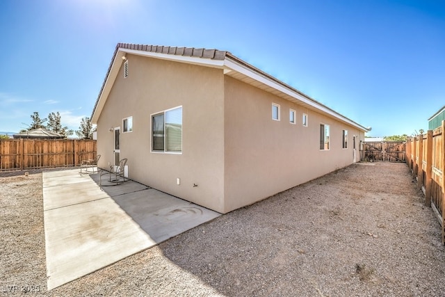 view of property exterior with stucco siding, a fenced backyard, and a patio area