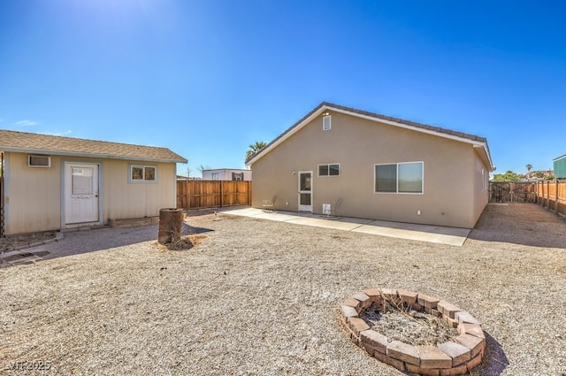 rear view of property featuring a patio area, a fenced backyard, and an outdoor fire pit
