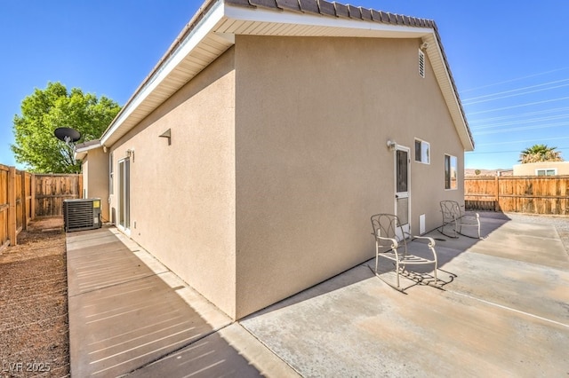 view of home's exterior featuring stucco siding, a patio area, central AC, and a fenced backyard