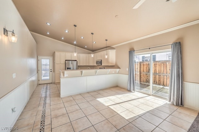 kitchen with stainless steel appliances, wainscoting, a peninsula, light tile patterned flooring, and crown molding