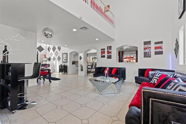 living area with arched walkways, a high ceiling, recessed lighting, and light tile patterned flooring
