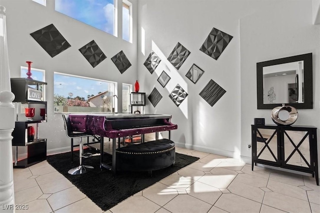 living area with a towering ceiling, tile patterned floors, and baseboards