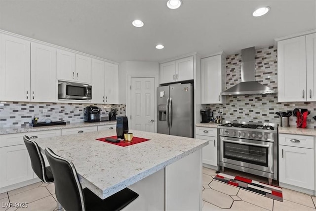 kitchen featuring stainless steel appliances, wall chimney exhaust hood, white cabinetry, tasteful backsplash, and recessed lighting