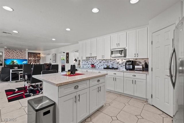 kitchen with stainless steel appliances, white cabinetry, open floor plan, recessed lighting, and a kitchen island
