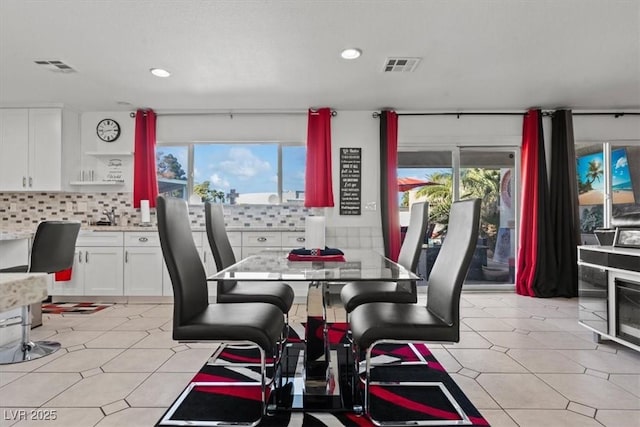 dining space featuring healthy amount of natural light, light floors, and recessed lighting