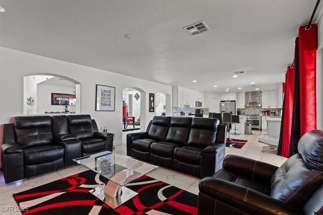 living room featuring arched walkways, light tile patterned floors, and recessed lighting