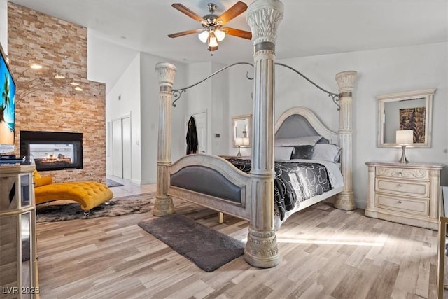bedroom featuring wood finished floors, a multi sided fireplace, and baseboards