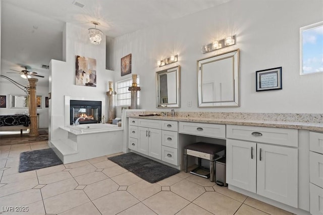 full bathroom with ensuite bathroom, a ceiling fan, a multi sided fireplace, vanity, and healthy amount of natural light