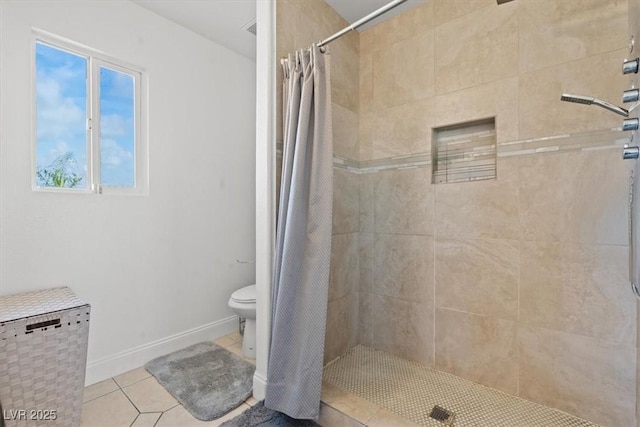 bathroom featuring tile patterned flooring, a tile shower, and toilet