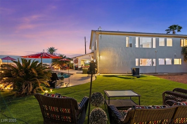 back of house featuring a patio, a lawn, stucco siding, and central AC