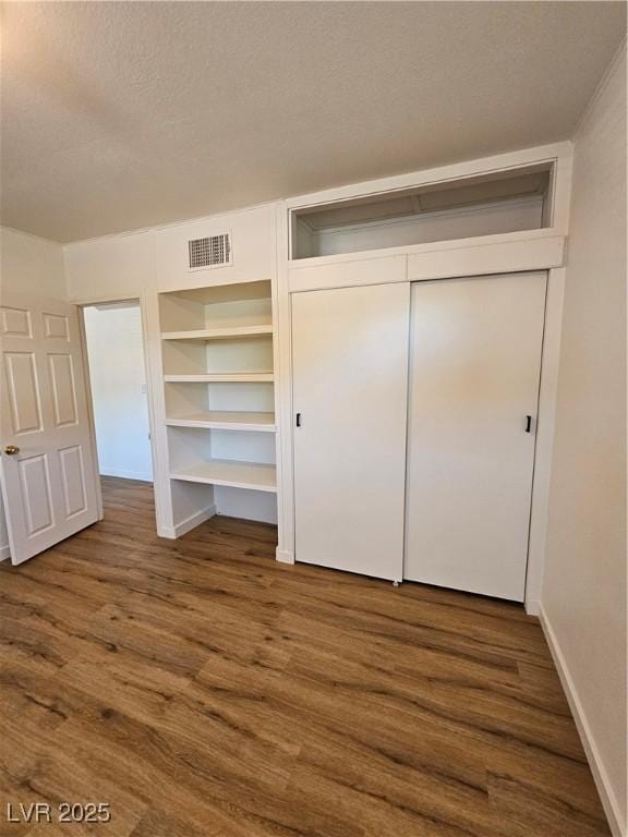 131 Copper St, Henderson, NV 89015 - unfurnished bedroom featuring dark wood-style floors, a closet, baseboards, and a textured ceiling