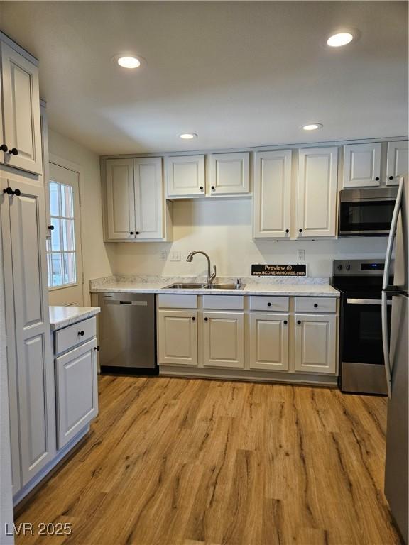 131 Copper St, Henderson, NV 89015 - kitchen featuring a sink, appliances with stainless steel finishes, light countertops, light wood finished floors, and recessed lighting