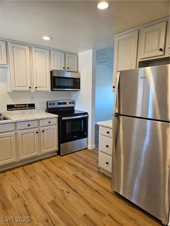 131 Copper St, Henderson, NV 89015 - kitchen with stainless steel appliances, light wood-style floors, white cabinetry, recessed lighting, and baseboards