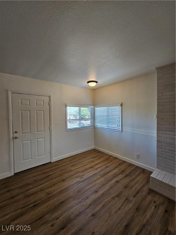 empty room featuring dark wood-type flooring, baseboards, and a textured ceiling