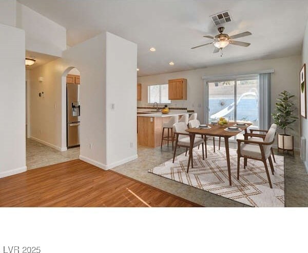 dining space featuring arched walkways, light wood finished floors, healthy amount of natural light, ceiling fan, and recessed lighting