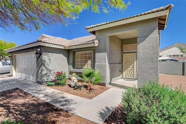 view of front of house featuring an attached garage, a tiled roof, stucco siding, fence, and driveway