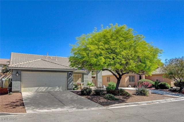 view of front of house featuring a tiled roof, an attached garage, stucco siding, and concrete driveway
