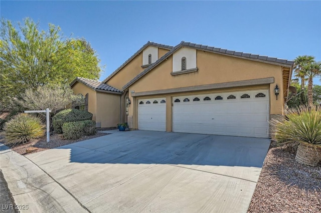 view of front of property with stucco siding, an attached garage, concrete driveway, and a tiled roof