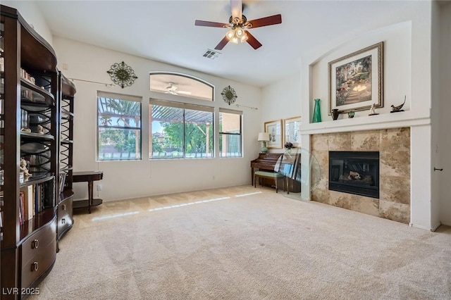 living area featuring ceiling fan, carpet floors, and a tiled fireplace