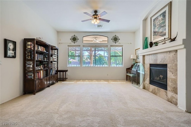 sitting room with a ceiling fan, carpet flooring, and a tile fireplace