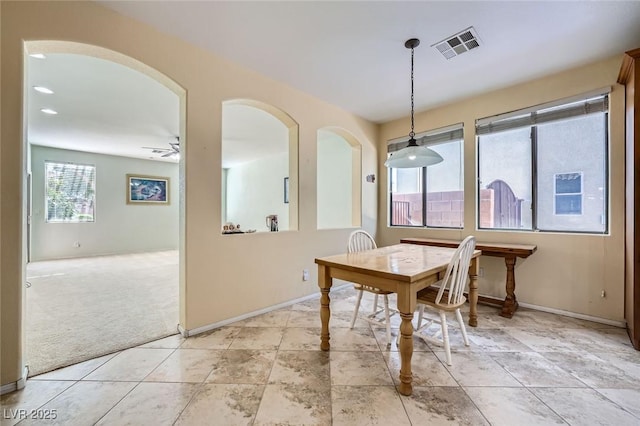 dining space with light colored carpet, baseboards, arched walkways, and a ceiling fan