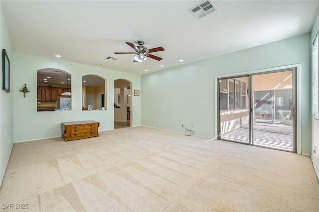 unfurnished living room featuring arched walkways, ceiling fan, carpet floors, recessed lighting, and baseboards