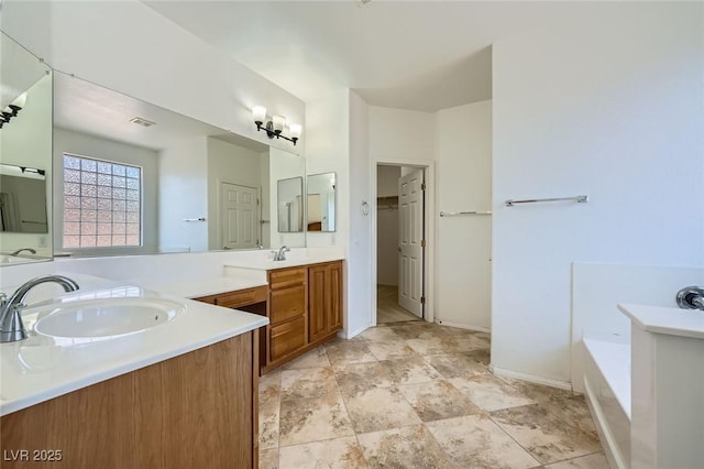 full bath with two vanities, a garden tub, and baseboards