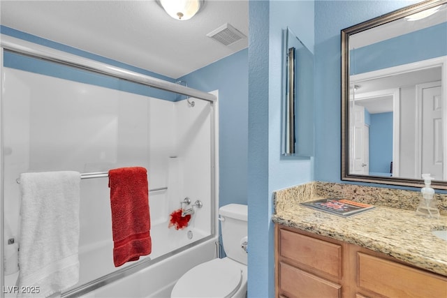 bathroom featuring vanity, bath / shower combo with glass door, toilet, and a textured wall