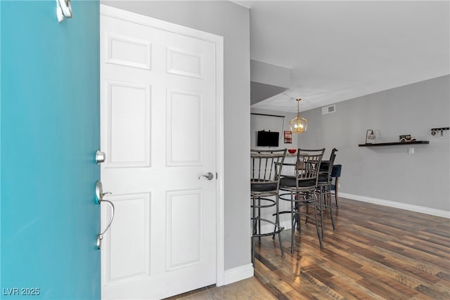 foyer featuring baseboards, wood finished floors, and a chandelier