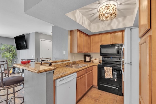 kitchen with black appliances, a sink, a peninsula, a breakfast bar area, and light stone counters