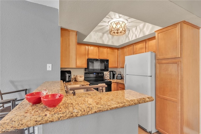 kitchen with black appliances, a peninsula, light stone counters, a textured wall, and a sink