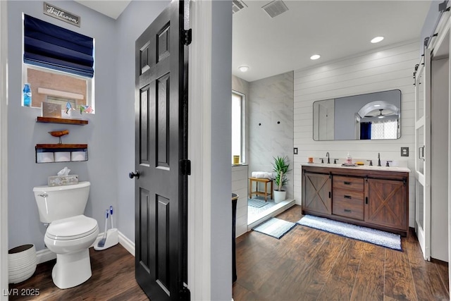 full bath with wood finished floors, toilet, double vanity, recessed lighting, and baseboards