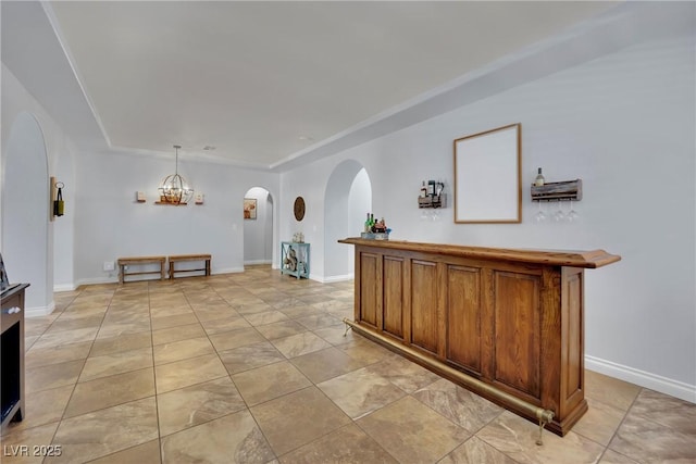 interior space with arched walkways, a chandelier, baseboards, and a raised ceiling
