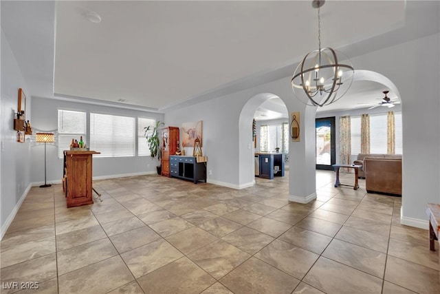 interior space featuring arched walkways, light tile patterned flooring, baseboards, a chandelier, and ceiling fan