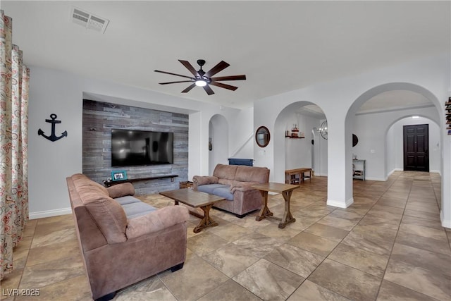 living area featuring arched walkways, a ceiling fan, and baseboards