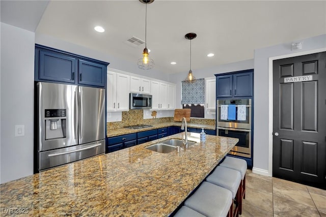 kitchen featuring appliances with stainless steel finishes, a sink, tasteful backsplash, blue cabinets, and recessed lighting
