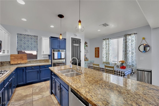kitchen with a sink, blue cabinets, stainless steel appliances, hanging light fixtures, and recessed lighting