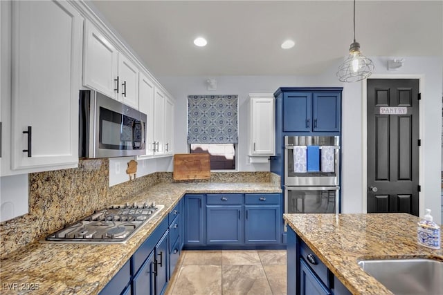 kitchen featuring appliances with stainless steel finishes, blue cabinets, white cabinetry, light stone counters, and recessed lighting