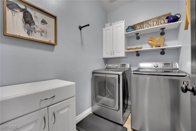 clothes washing area with separate washer and dryer, cabinet space, and baseboards
