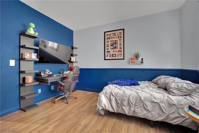 bedroom with wood finished floors, an office area, and baseboards