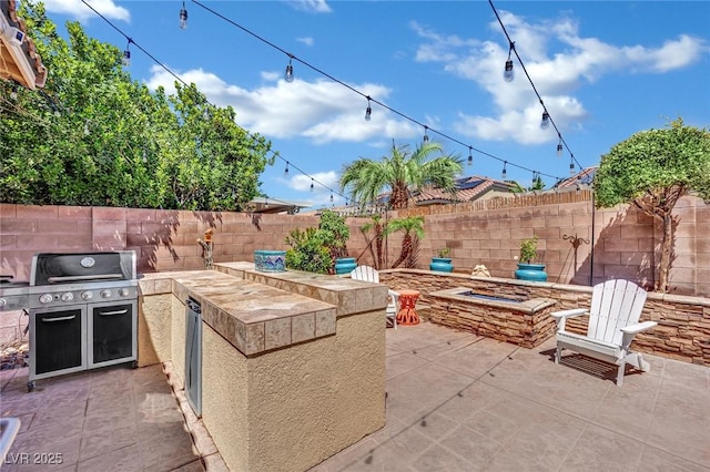 view of patio featuring an outdoor kitchen, a fire pit, a fenced backyard, and grilling area