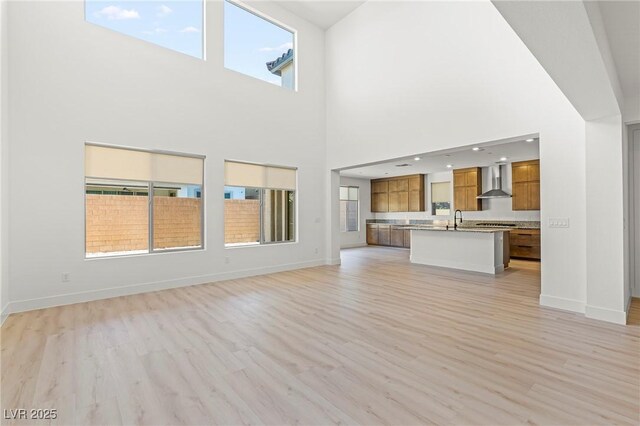 10851 Hanwicke Harbor Ave, Las Vegas, NV 89166 - unfurnished living room with light wood-style flooring and a towering ceiling