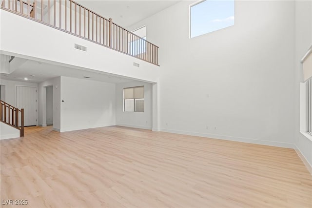 10851 Hanwicke Harbor Ave, Las Vegas, NV 89166 - unfurnished living room featuring light wood finished floors, a high ceiling, stairway, and baseboards