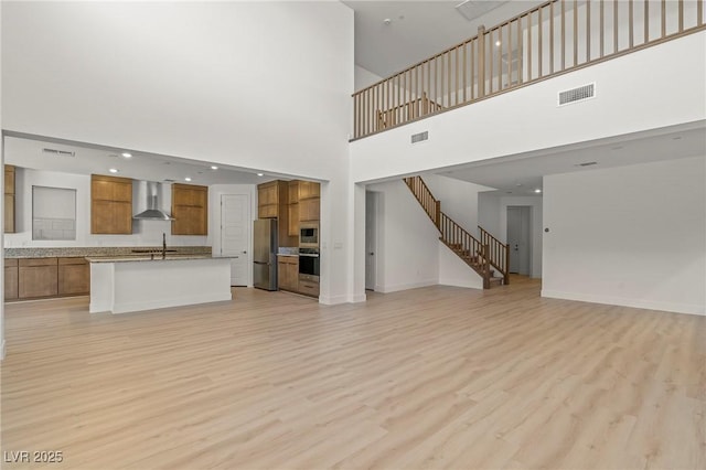 10851 Hanwicke Harbor Ave, Las Vegas, NV 89166 - unfurnished living room featuring a sink, light wood finished floors, stairs, baseboards, and a towering ceiling