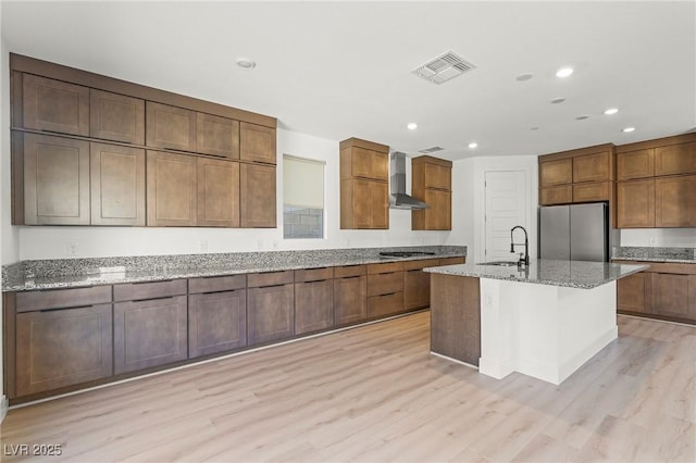 10851 Hanwicke Harbor Ave, Las Vegas, NV 89166 - kitchen with stainless steel appliances, wall chimney range hood, a sink, light wood finished floors, and recessed lighting