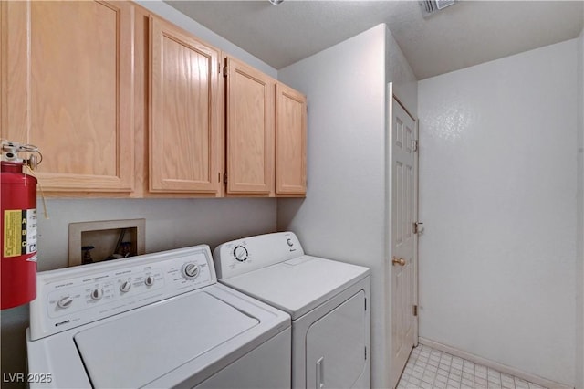 clothes washing area with washer and clothes dryer, cabinet space, and baseboards