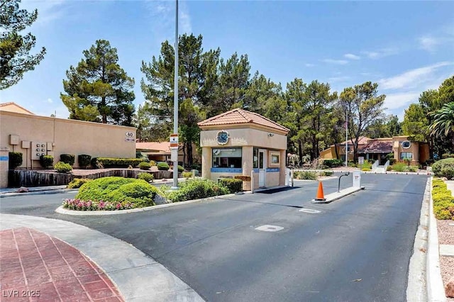 view of asphalt street featuring curbs and a gated entry